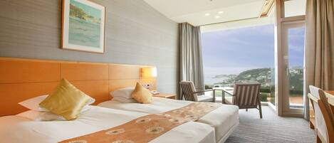 A hotel room with two beds, a large window with a view, a desk, and a chair.