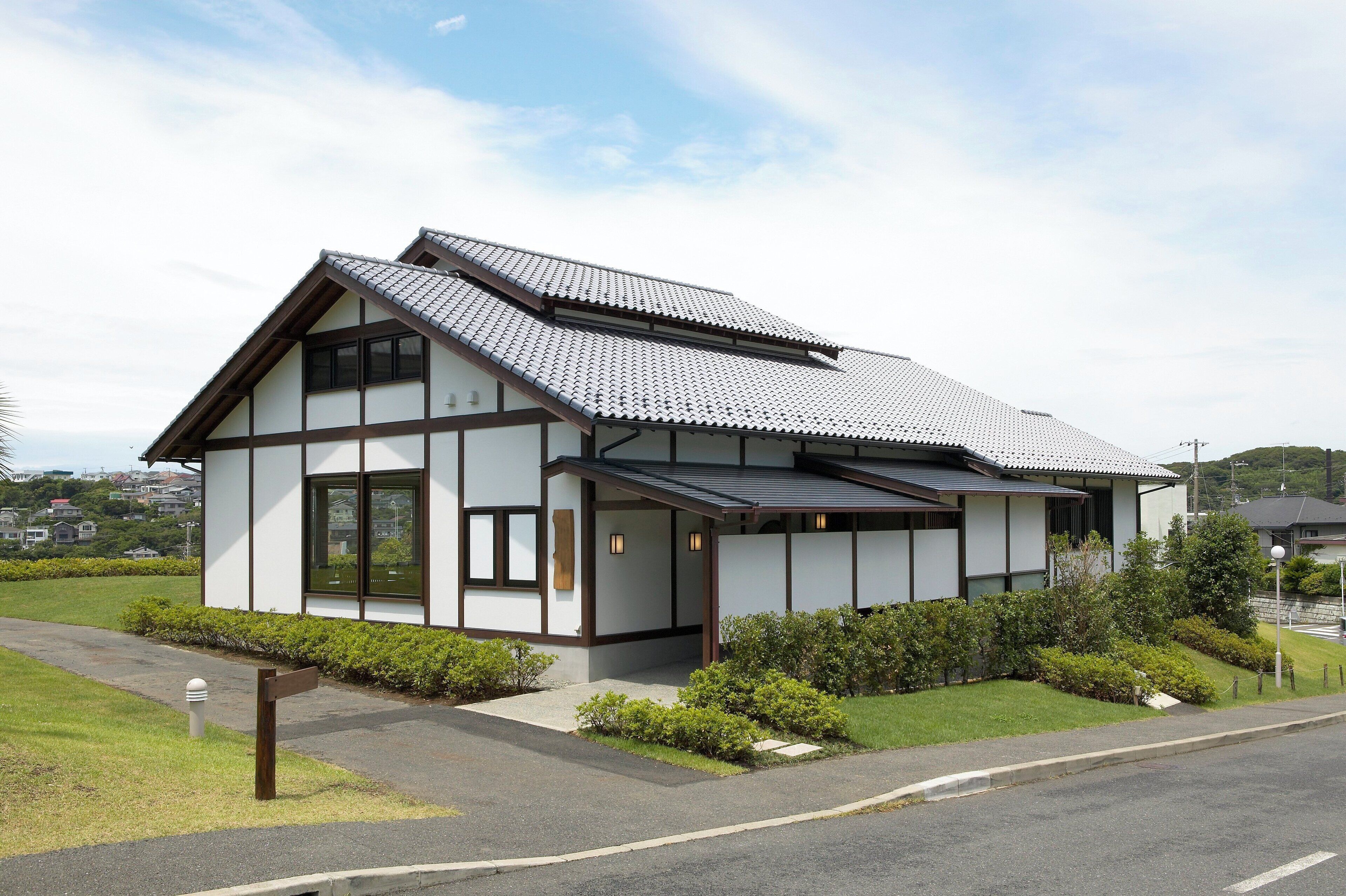 A modern two-story house with a sloped roof, large windows, and a well-maintained garden.