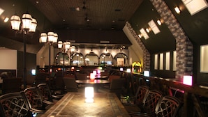 An indoor dining area with a high ceiling, multiple tables, and chairs. - the b hachioji (Hachioji)