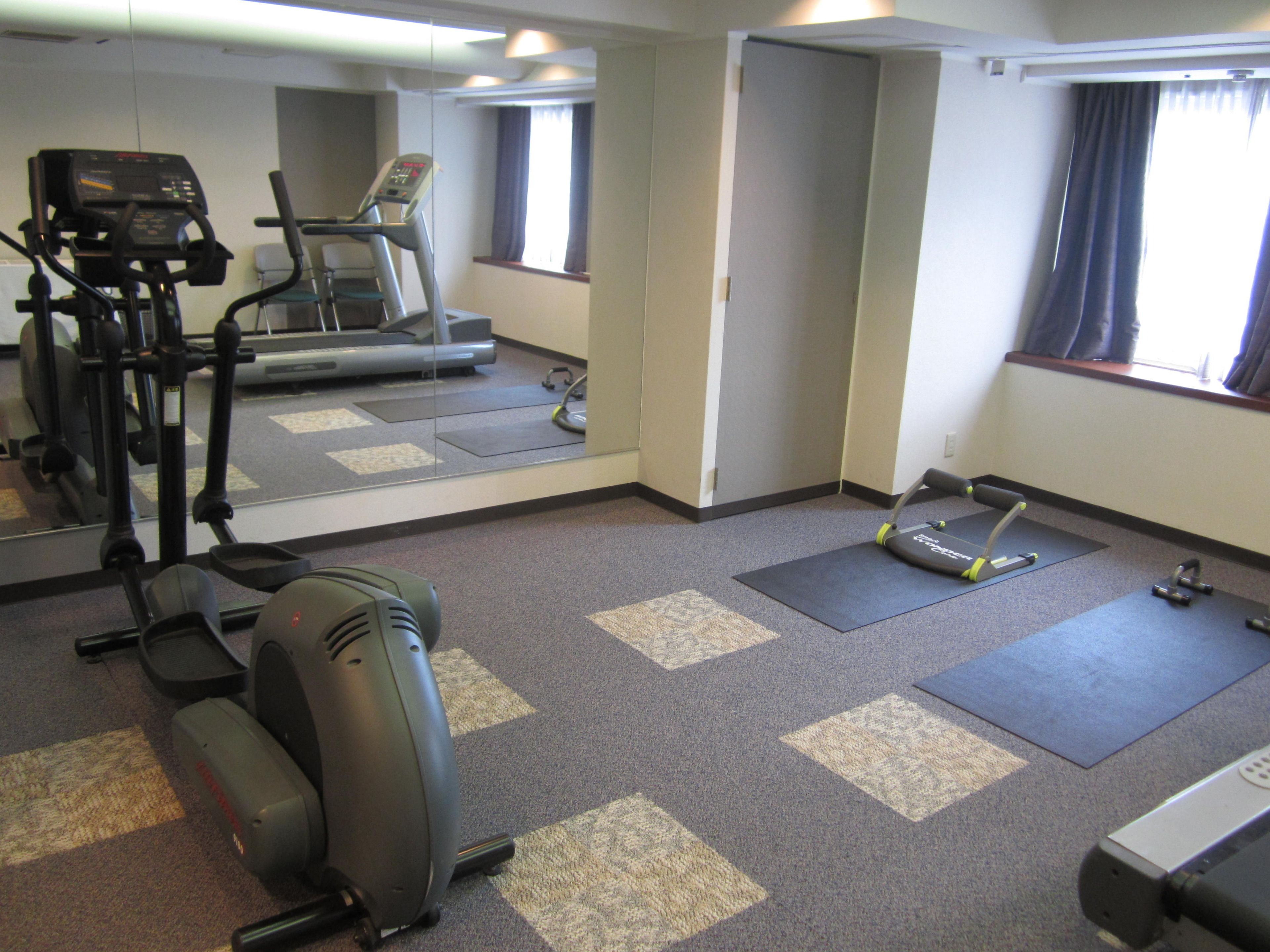 Un gimnasio con equipo de ejercicio, incluyendo una cinta de correr, una elíptica y pesas.