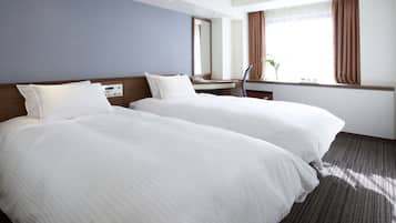A hotel room with two beds, a desk, a chair, a window with curtains, and a plant.