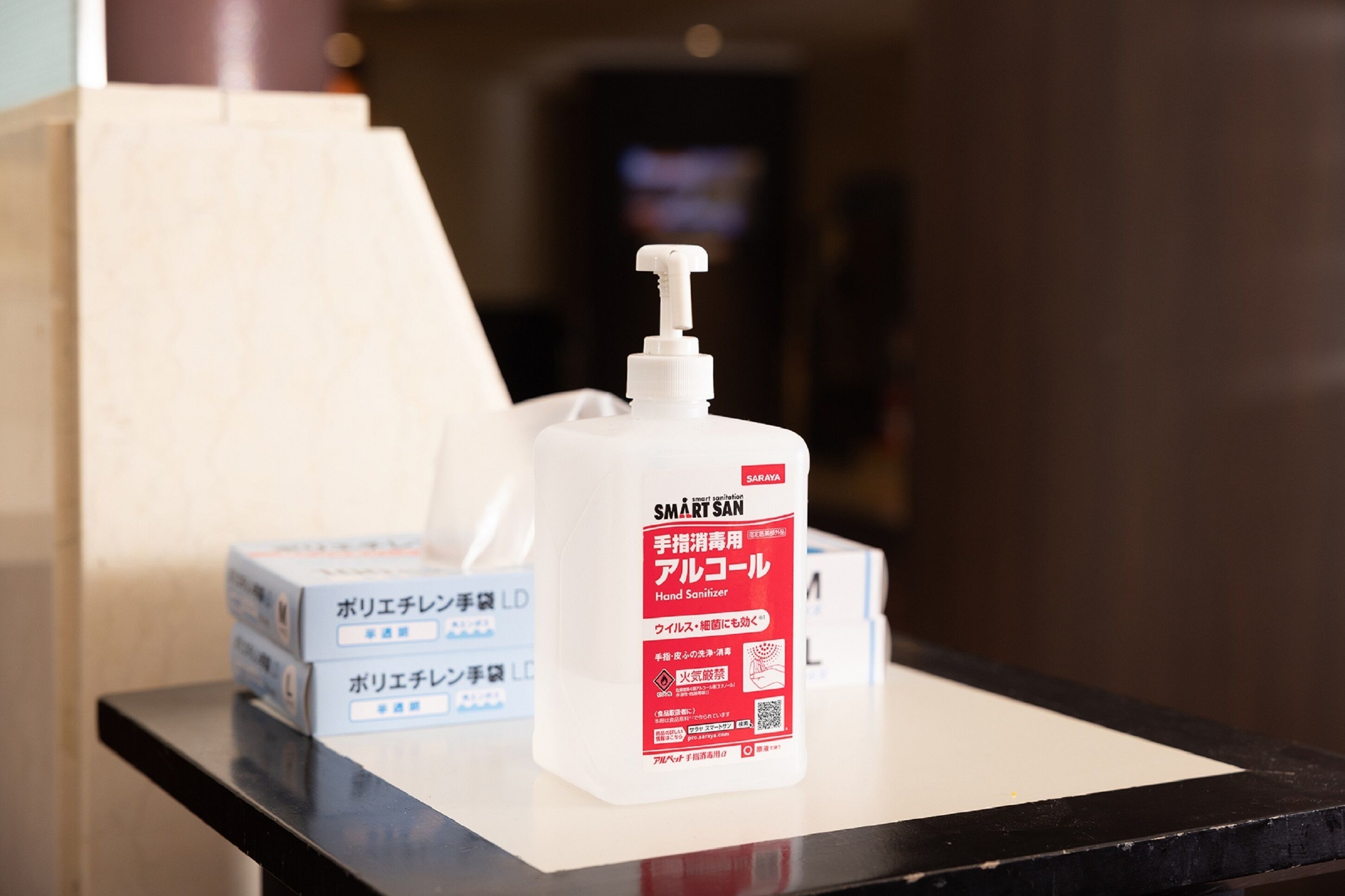 Een fles handdesinfecterend middel met Japanse tekst op een tafel, samen met dozen met vergelijkbare tekst.
