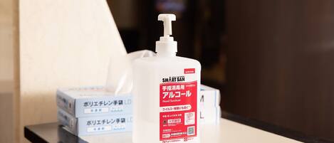 A hand sanitizer bottle with Japanese text on a table, accompanied by boxes with similar text.