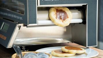 Ein Frühstückstisch mit einer Waffelmaschine und einem Teller für Pfannkuchen.