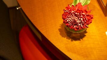 A wooden table with a red flower arrangement.