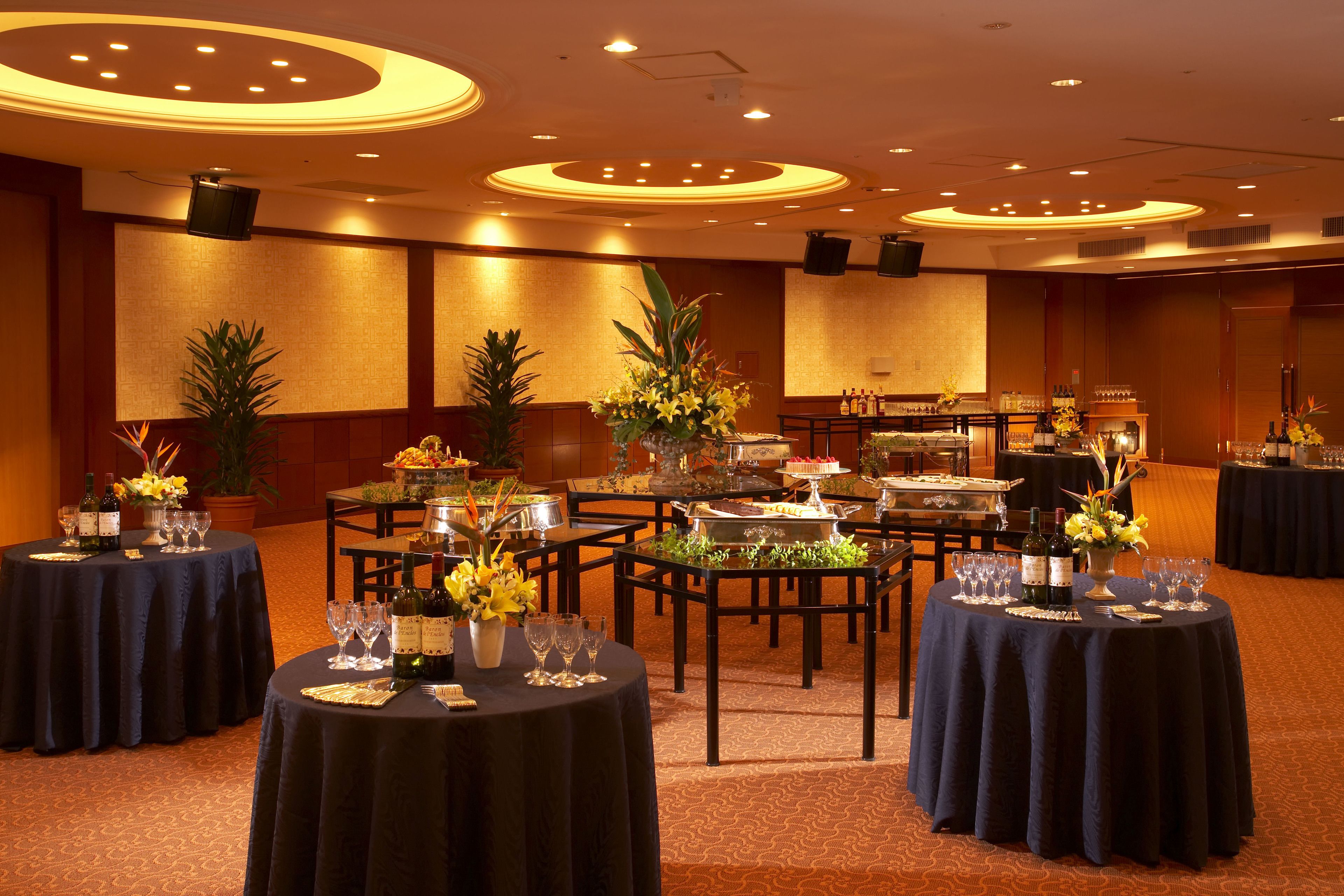A banquet hall with round tables set for dining, featuring floral centerpieces and wine glasses.