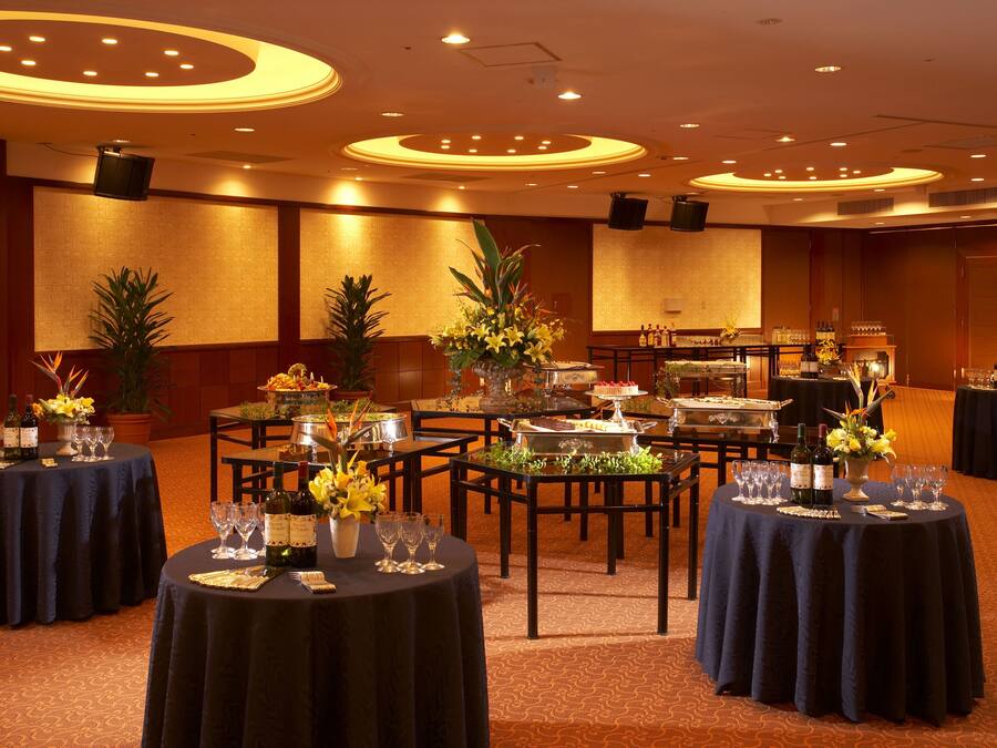 A banquet hall with round tables set for dining, featuring floral centerpieces and wine glasses.