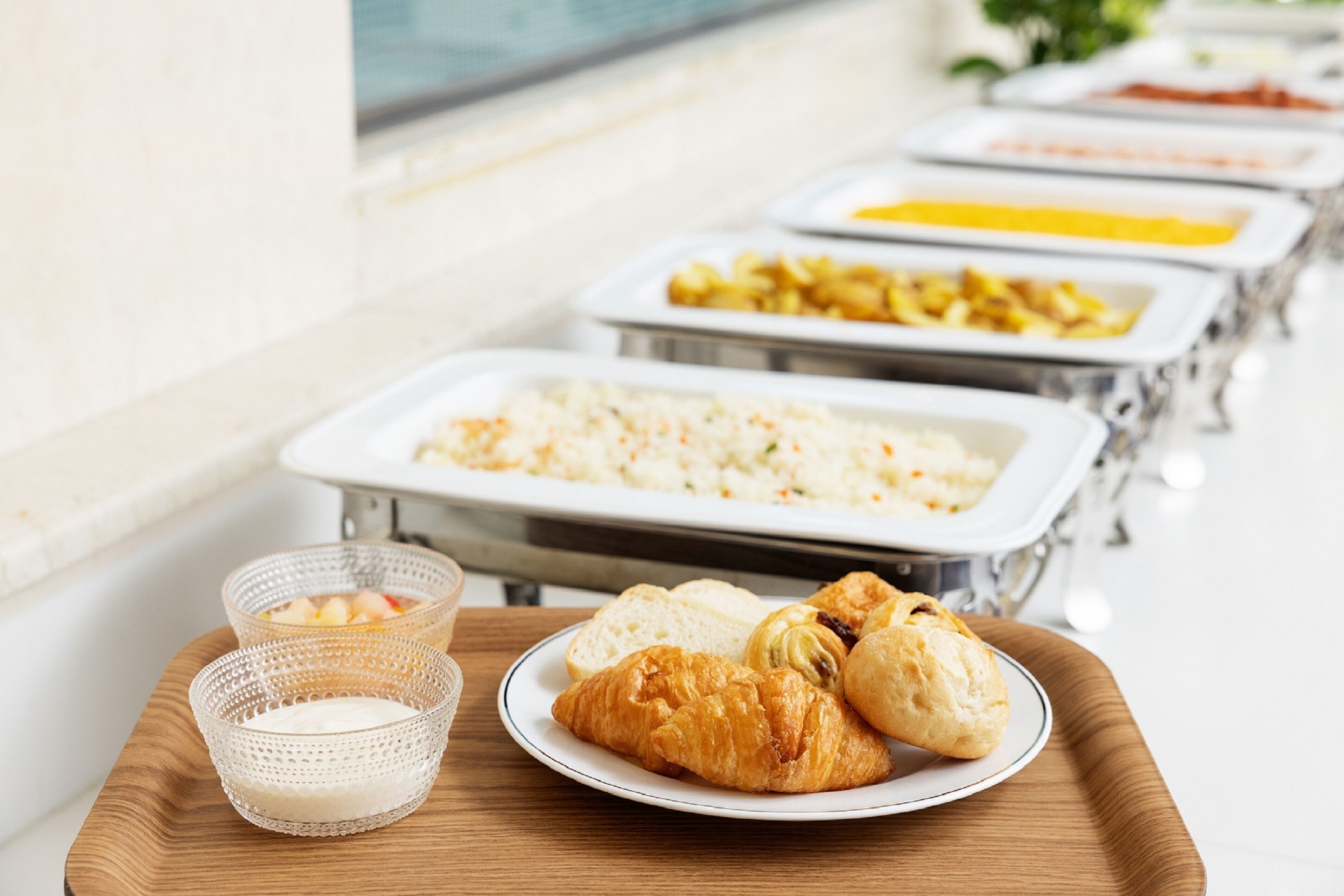 A buffet with various food options, including rice, fruits, and pastries.