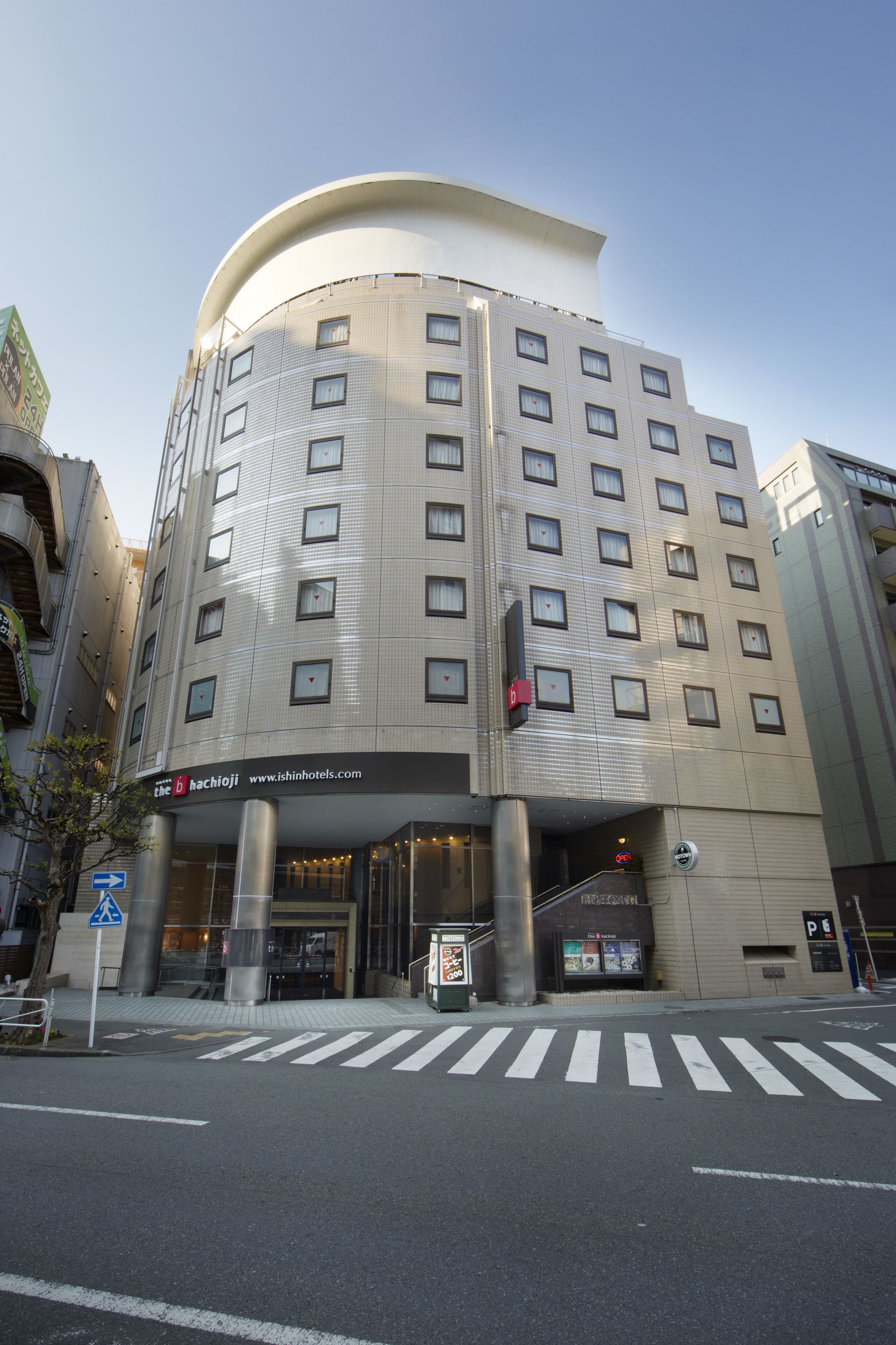 A modern hotel with a curved facade, multiple floors, and a prominent entrance with a staircase.