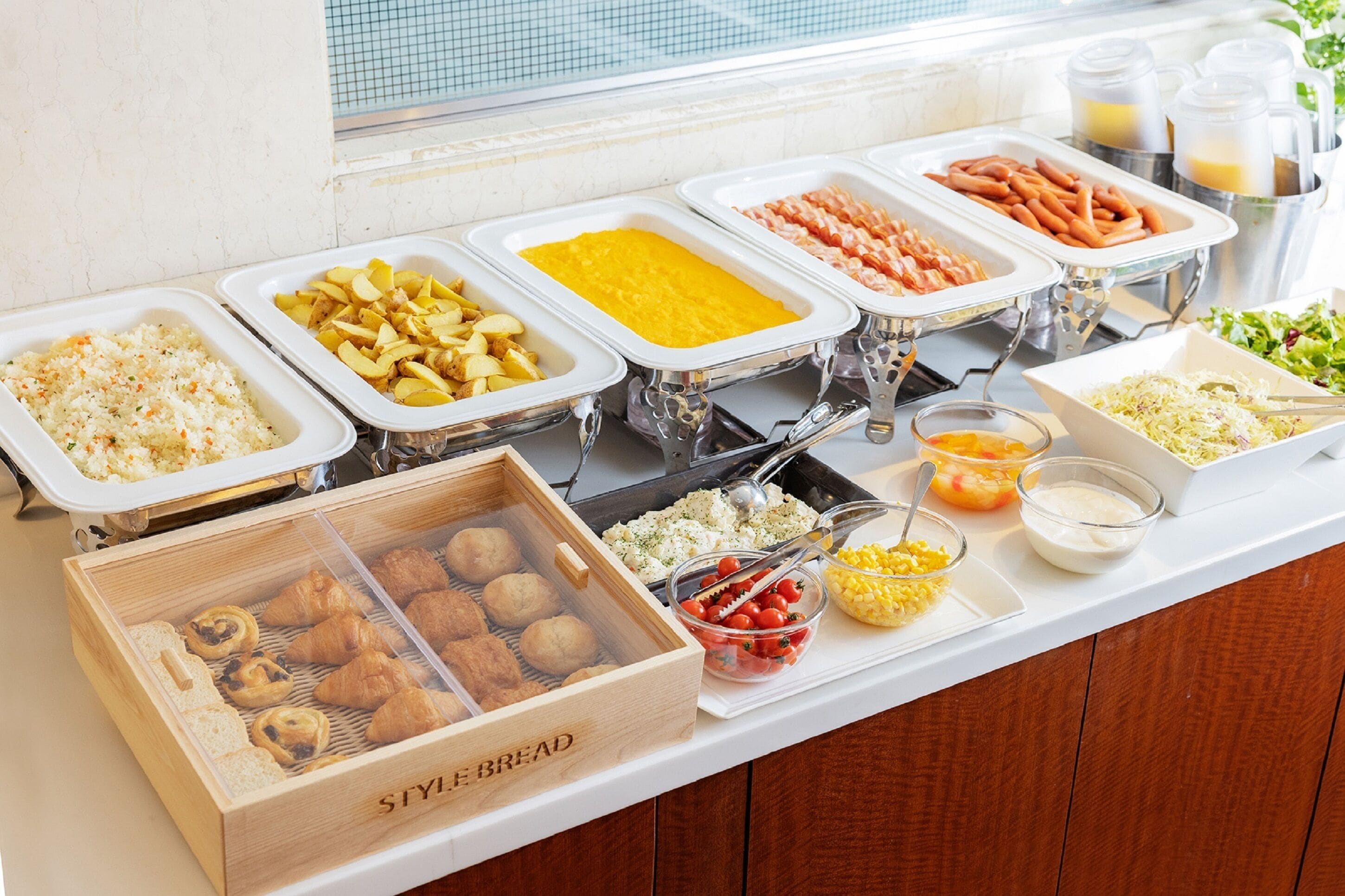 A buffet with various food items including rice, potatoes, sausages, and bread.