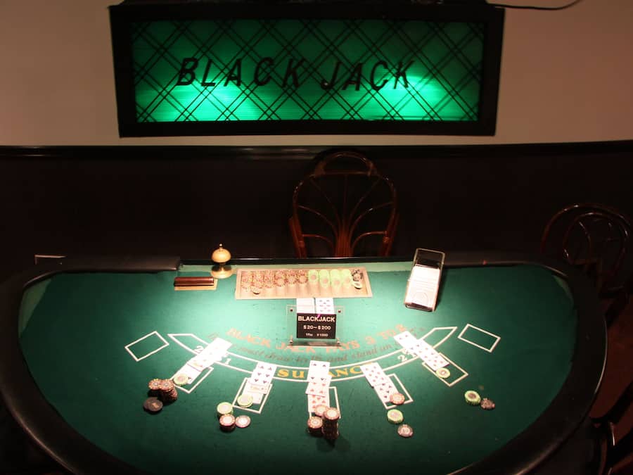 A blackjack table with chips and cards, a blackjack sign, and a bell.