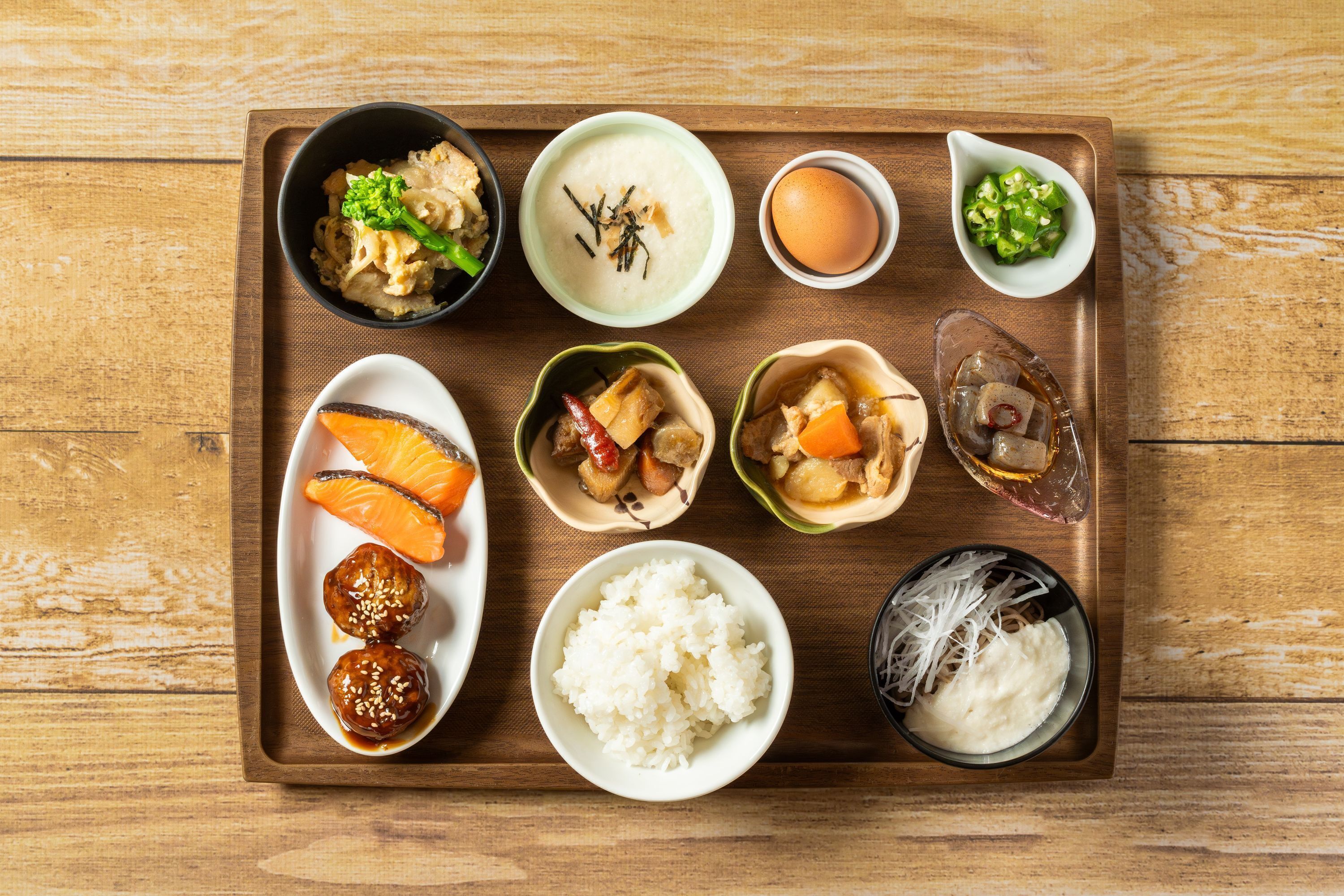 Una bandeja con diversos platos japoneses, como sushi, arroz y vegetales encurtidos.