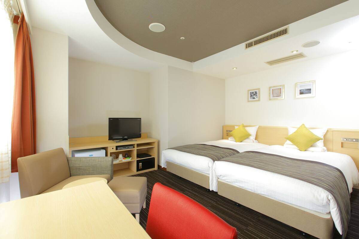 Habitación de hotel con dos camas, televisión, escritorio y silla.