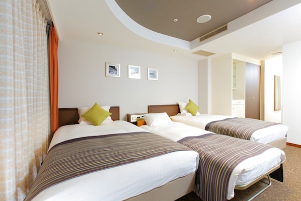 A hotel room with two beds, a headboard, a nightstand, and a wall-mounted TV.
