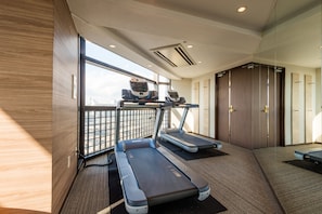 Une salle de sport moderne équipée de tapis de course, dotée d’une grande fenêtre et d’une porte.