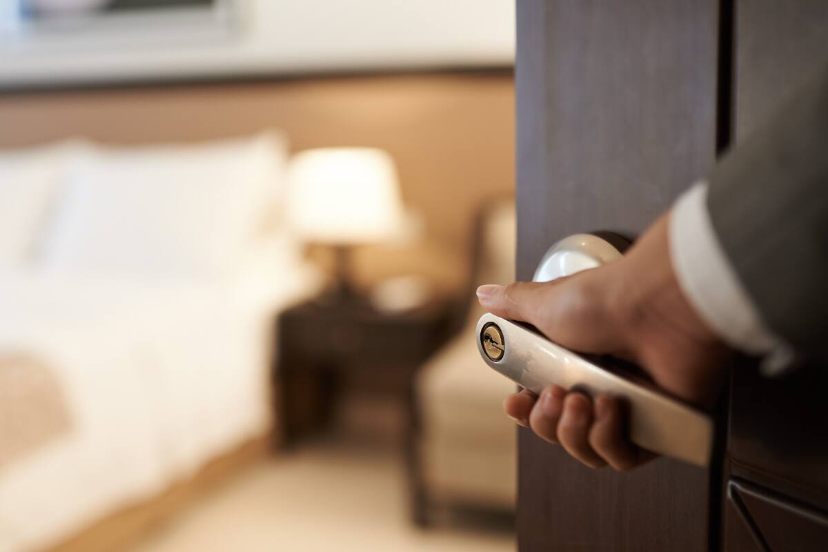 Una mano girando el pomo de una puerta en una habitación de hotel.