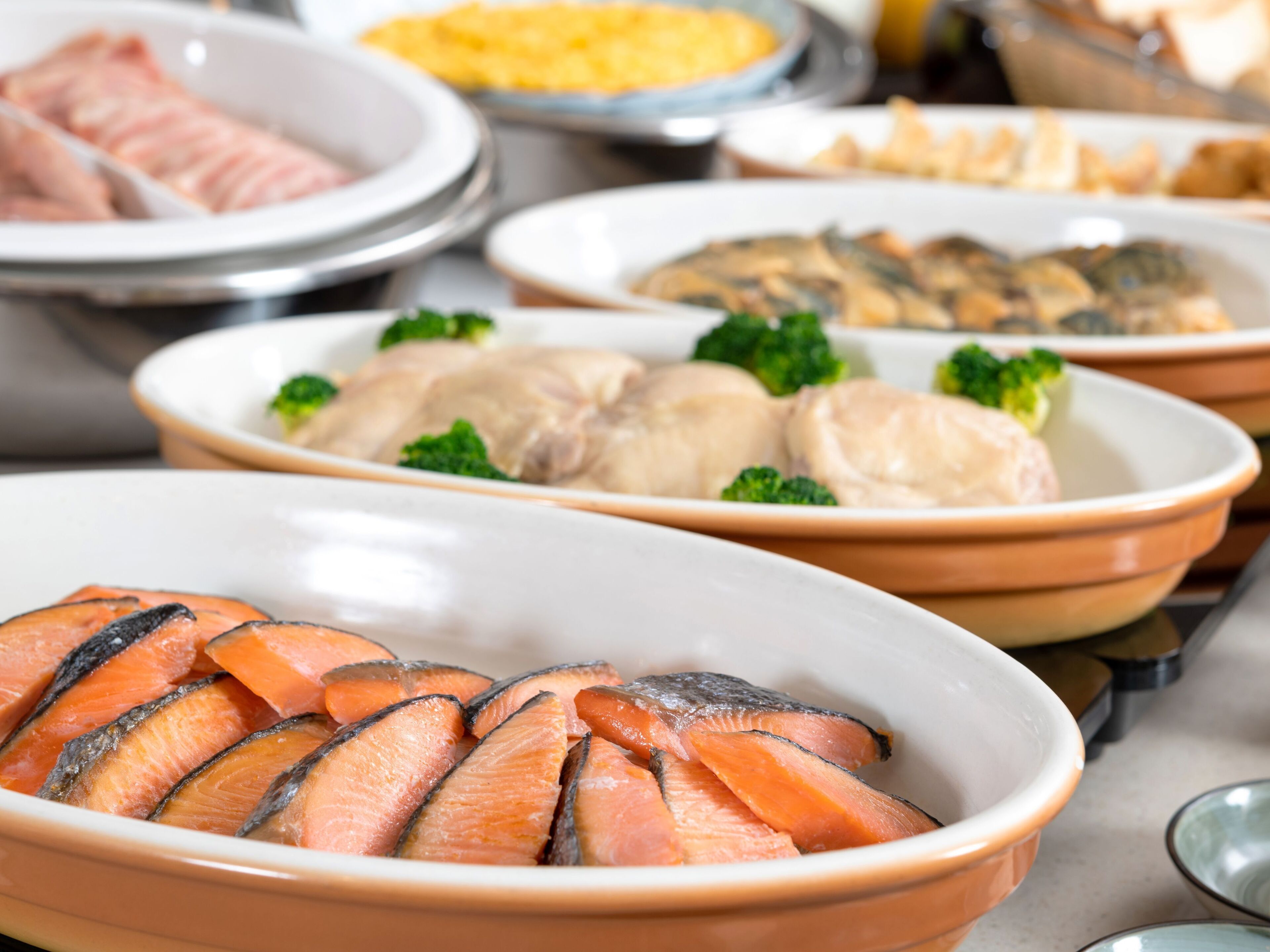 A variety of dishes including salmon, chicken, and other seafood, served on a buffet table.