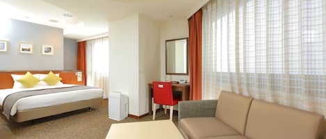 Une chambre d’hôtel avec un lit, un bureau, une chaise, un canapé et une petite table.