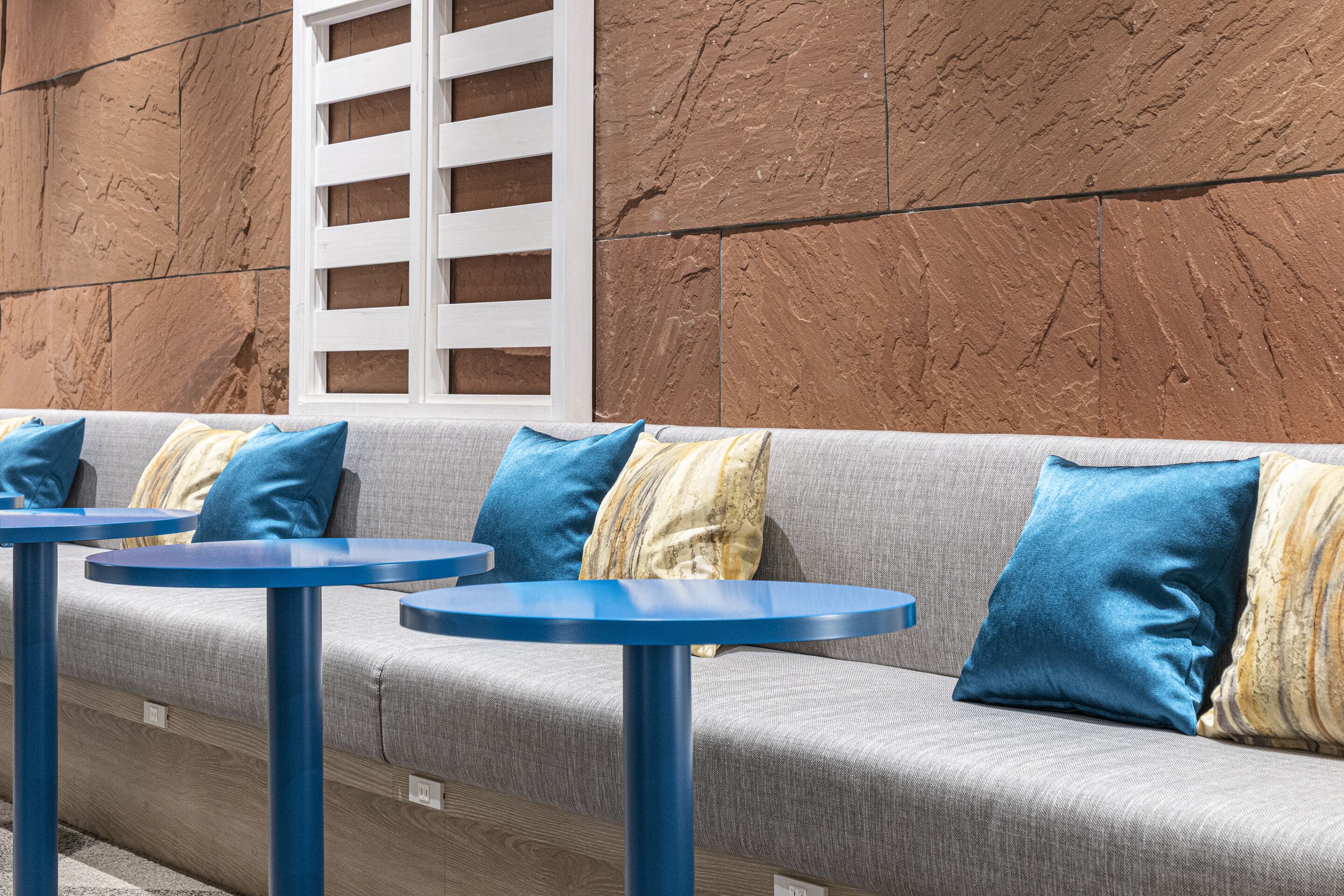 A seating area with a grey sofa, blue cushions, and round blue tables.