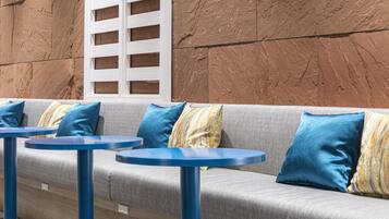 A seating area with a grey sofa, blue cushions, and round blue tables.