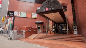 A hotel entrance with a red brick facade, a black awning, and a sign for 'the b Kobe'. - the b kobe (Kobe)