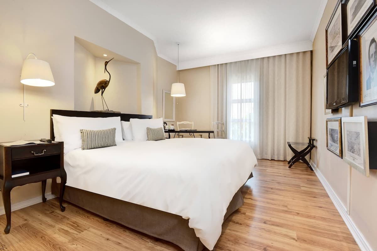 A hotel room with a large bed, bedside tables, a desk, and a chair.