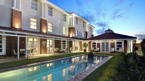 A modern two-story house with a swimming pool, outdoor seating, and a covered patio area.