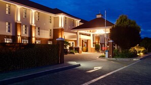 A hotel entrance with a covered walkway, brick facade, and a well-lit entrance area.