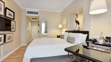 A hotel room with a large bed, bedside table, lamp, and framed pictures on the wall.