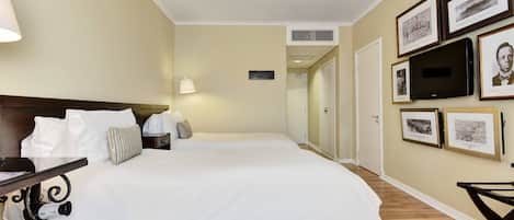 Una camera d'albergo con un letto grande, una scrivania con una lampada e una TV montata a parete.