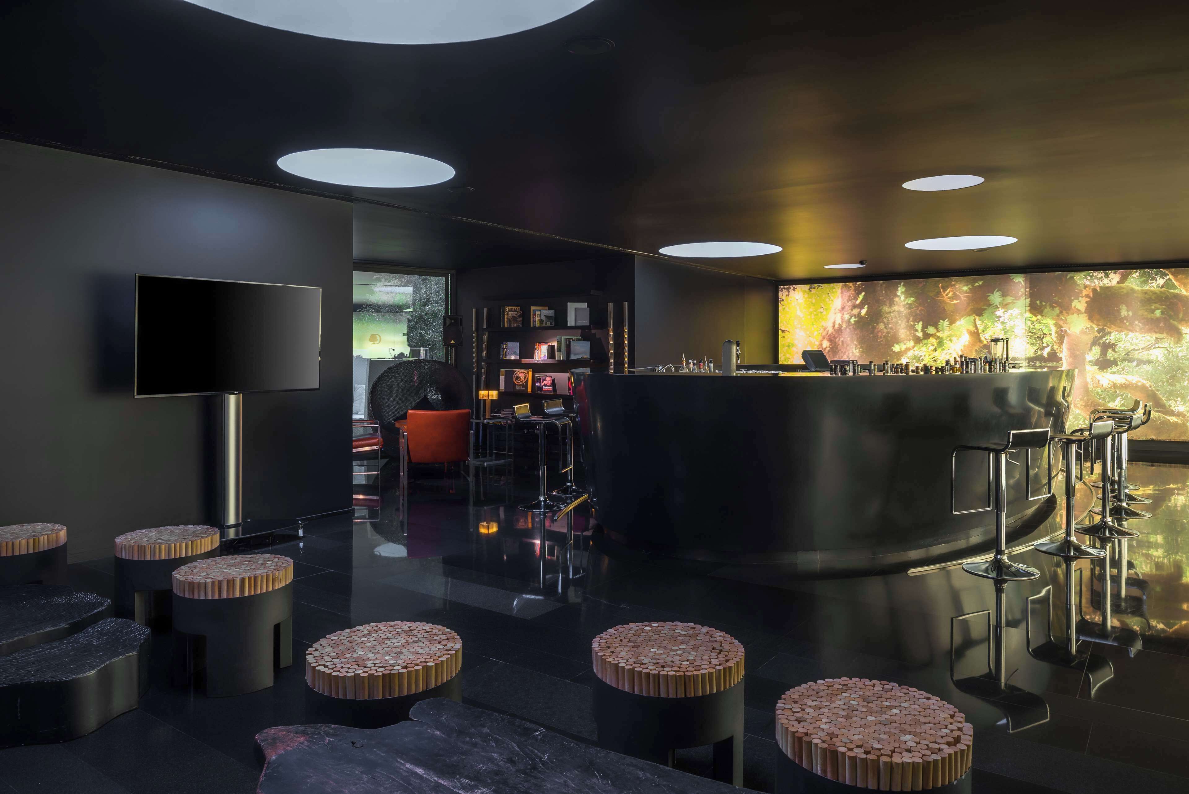 A modern bar area with a flat-screen TV, round stools, and a bar counter with stools.