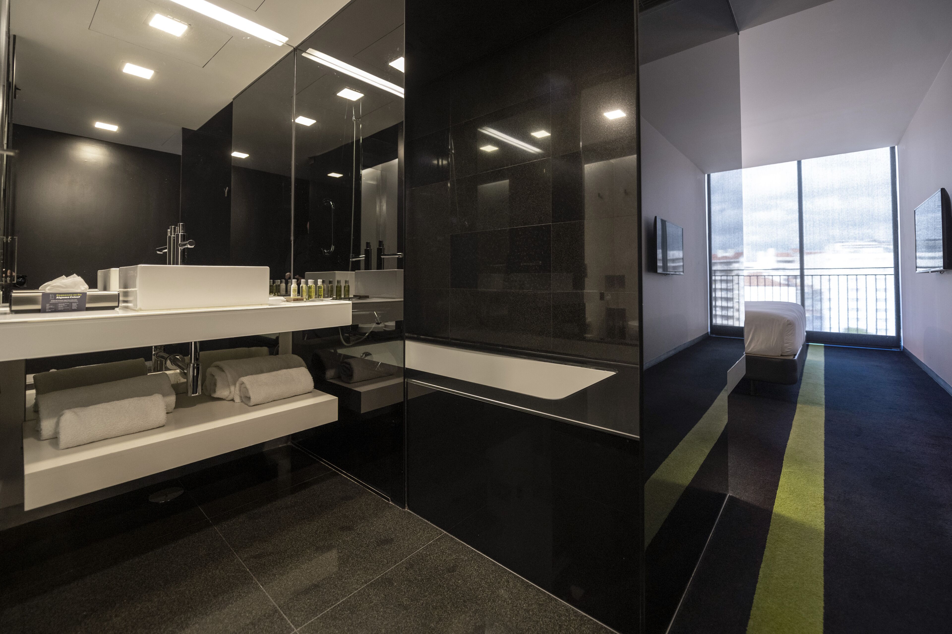 A modern bathroom with a large mirror, a white sink, and a black vanity.