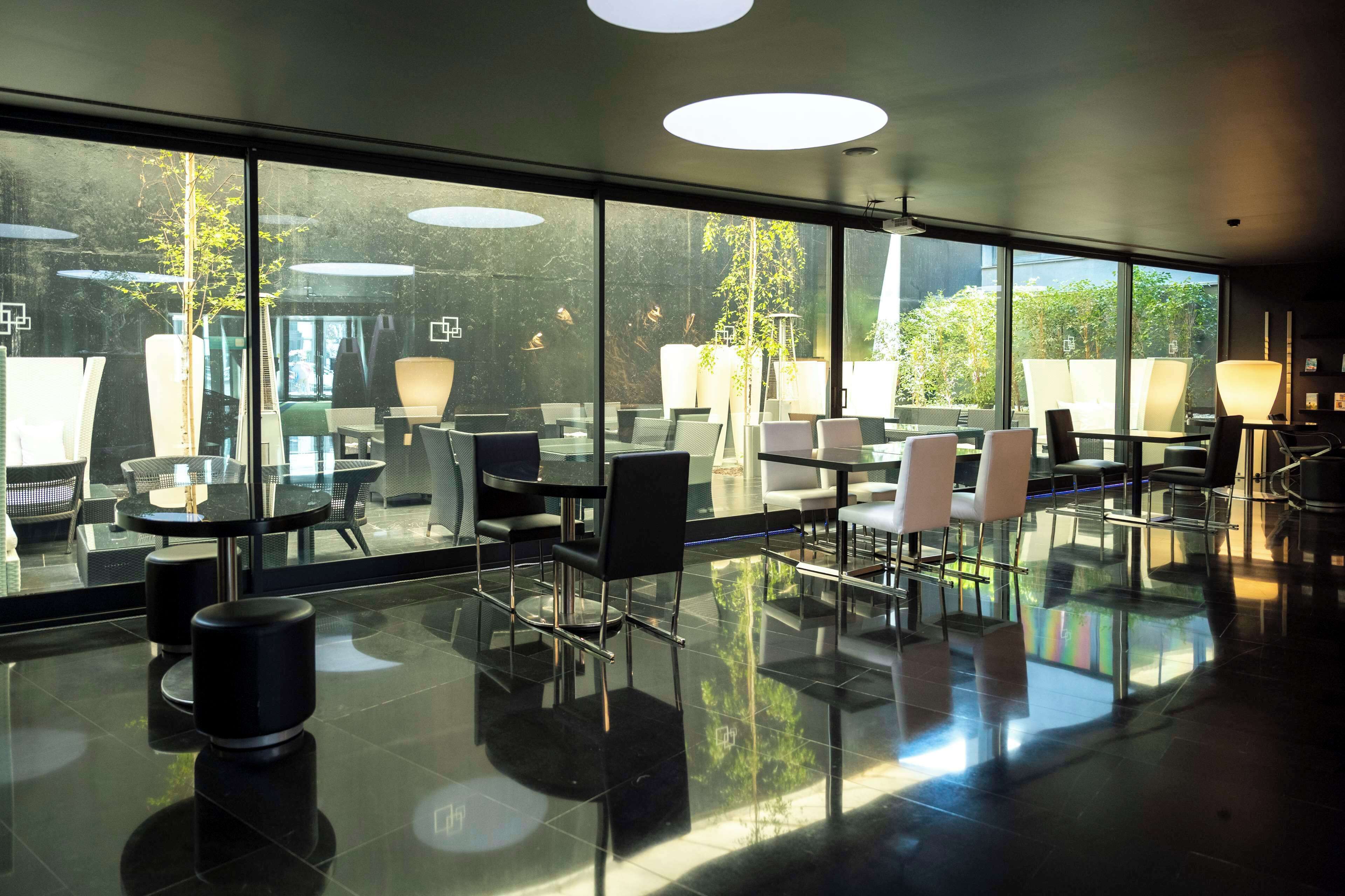 Un espacio interior moderno con paredes de vidrio, suelo reflectante y muebles contemporáneos.