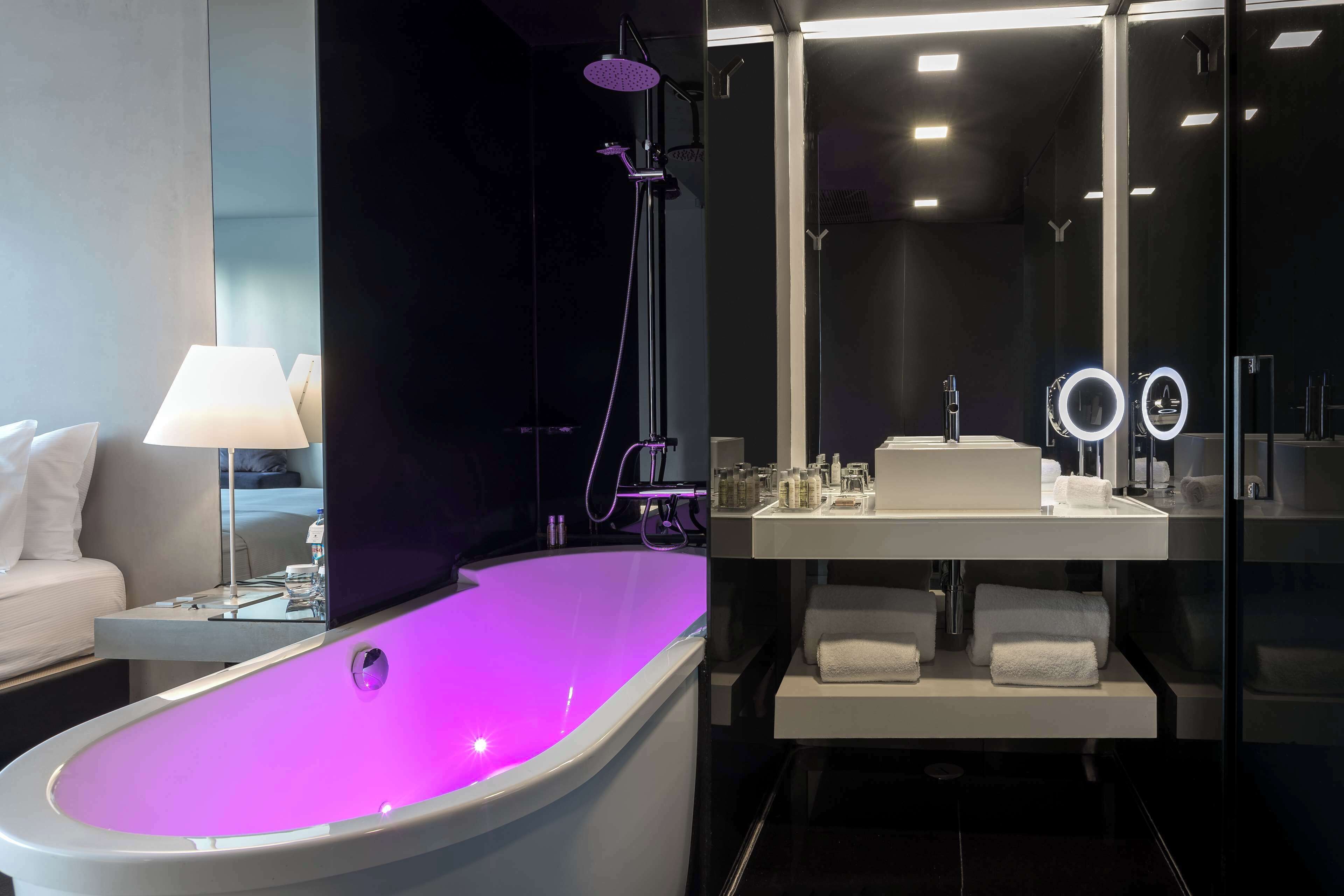 A modern bathroom with a large bathtub, a vanity with a mirror, and a shower area.