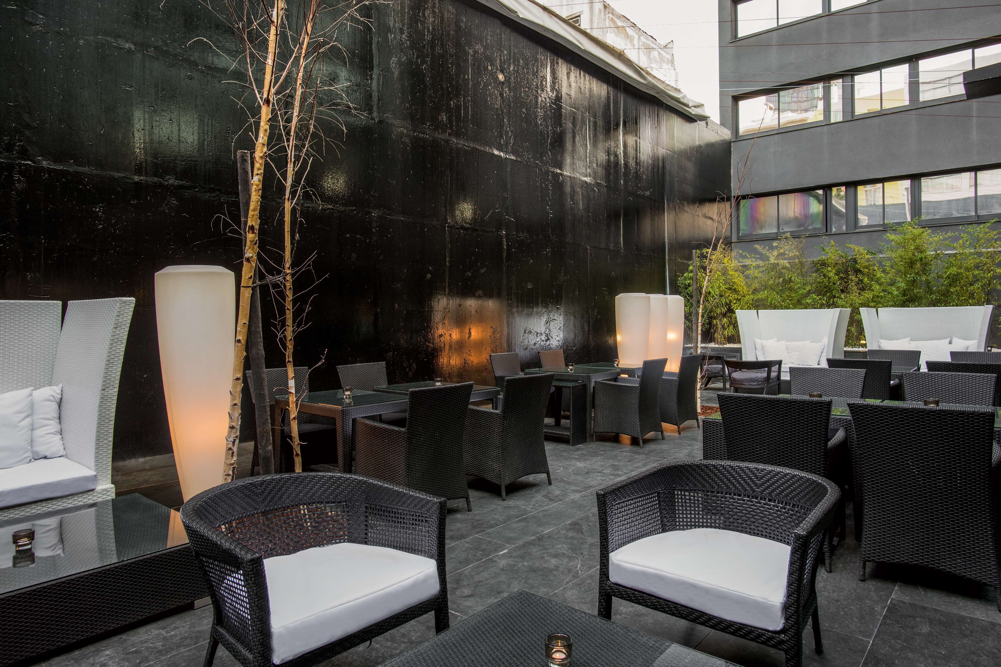 An outdoor patio with wicker furniture, a white sofa, and a tall tree.
