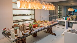 Una mesa larga con una variedad de alimentos y bebidas, rodeada de estantes con botellas y vasos.