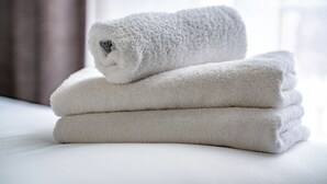 A stack of white towels on a bed. - Iveagh Lodge (Dublin)