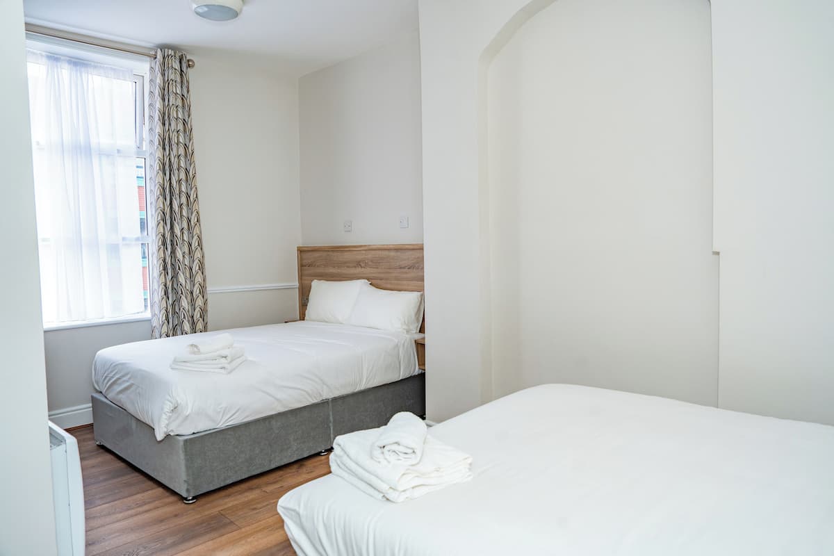 A hotel room with two beds, a wooden headboard, and a window with curtains.