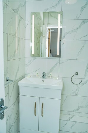 Een bad/douchecombinatie, een haardroger, handdoeken