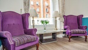 A room with two purple armchairs, a small table, and a vase with flowers. - Iveagh Lodge (Dublin)