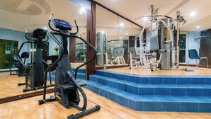 A gym with exercise equipment, a mirror, and blue-tiled steps.