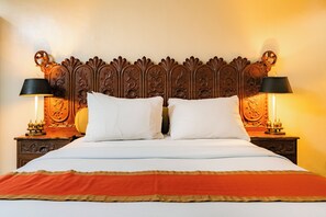 A bed with a wooden headboard, two bedside lamps, and a red bedspread. - Crown Regency Residences Davao (Davao)