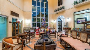 A spacious lobby with a large Christmas tree, wooden furniture, and a view of the cityscape through large windows.