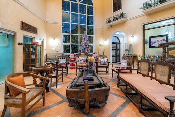 Eine geräumige Lobby mit einem großen Weihnachtsbaum, Holzmöbeln und Blick auf die Stadt durch große Fenster.
