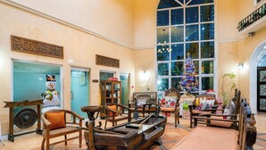 A lobby with a large Christmas tree, wooden furniture, and a view through a large window.