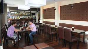 Un restaurant amb una zona de bar al fons, diverses taules i seients privats, i un disseny interior modern.