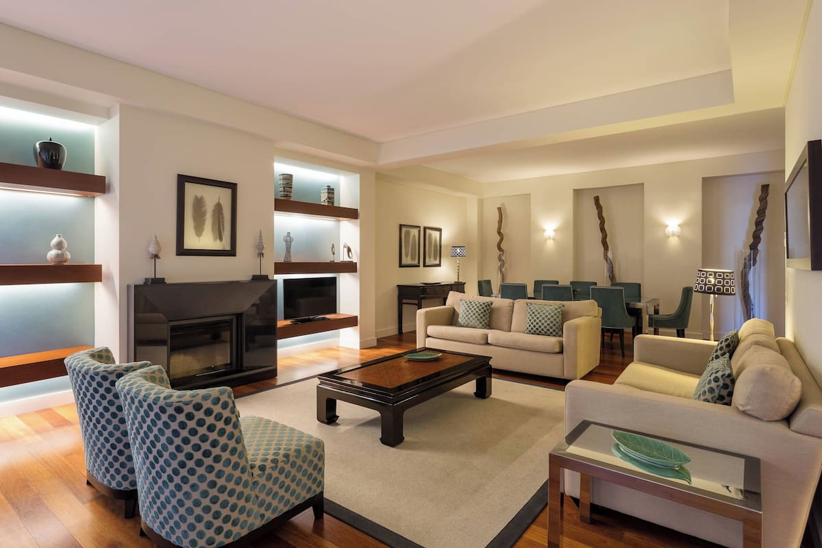 Una sala de estar moderna con chimenea, sofás, sillones y una mesa de centro.