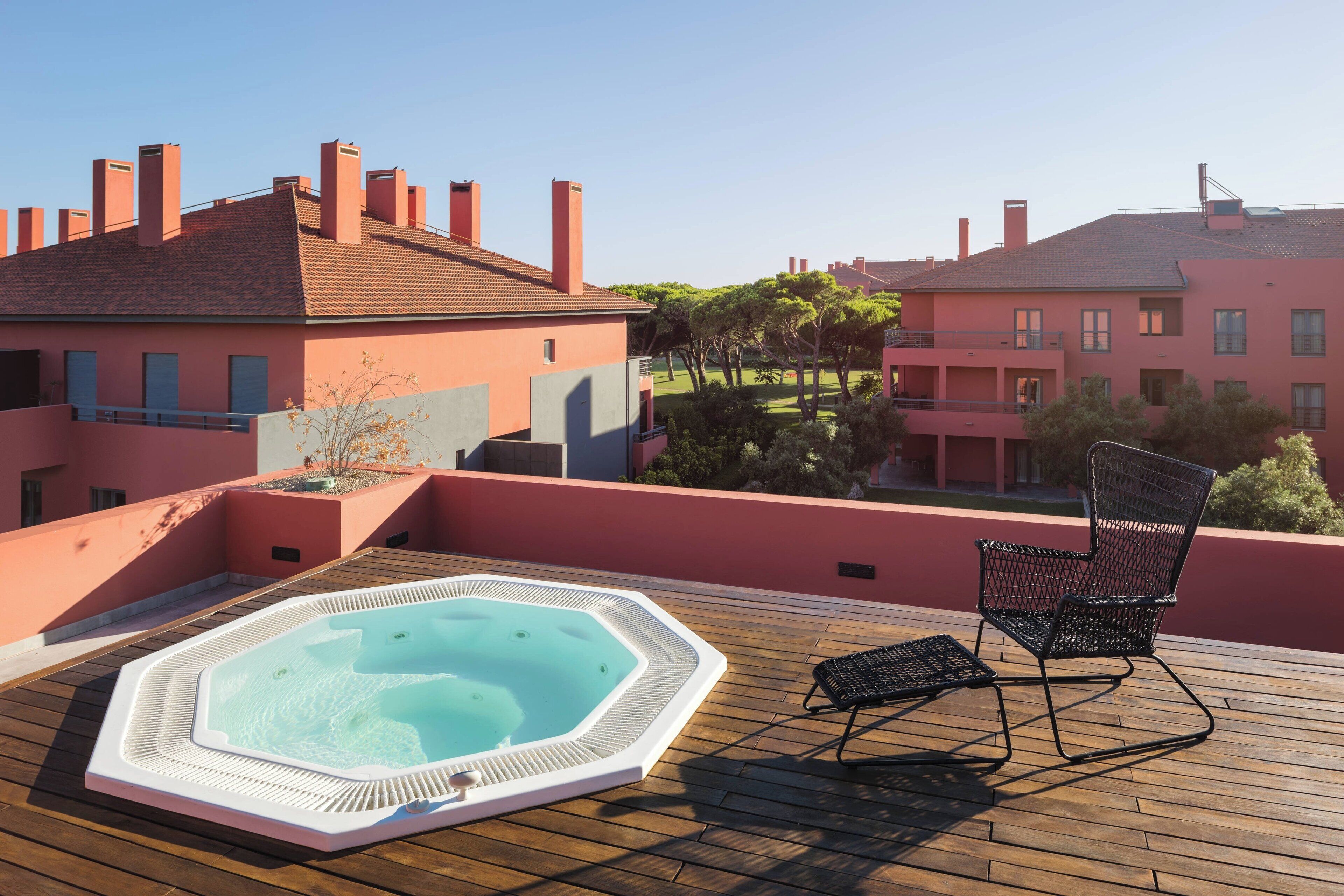 A rooftop with a hot tub, a lounge chair, and a view of buildings.
