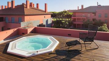 A rooftop with a hot tub, a lounge chair, and a view of buildings.