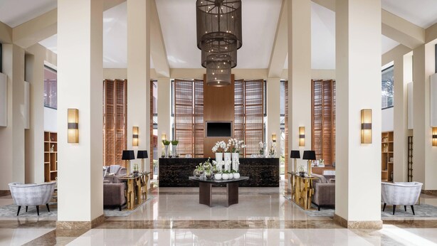 Un vestíbulo amplio con mostrador de recepción central, iluminación decorativa y un moderno candelabro.